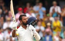 FILE: India's Cheteshwar Pujara kisses his helmet after reaching his century (100 runs) during the first day of the fourth Test against Australia at the Sydney Cricket Ground in Sydney on 3 January 2019. Picture: AFP