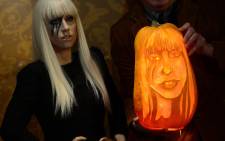 Pumpkin carver Hugh McCahon carves a pumpkin in the likeness of US singer Lady Gaga in front of her wax figure at Madame Tussauds in New York on October 22, 2013. AFP PHOTO/Emmanuel Dunand