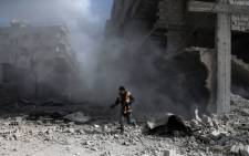 FILE: A civil defence volunteer, known as the White Helmets, checks the site of a regime air strike in the rebel-held town of Saqba, in the besieged Eastern Ghouta region. Picture: AFP.