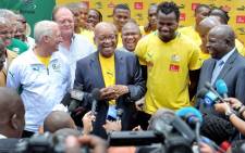 President Jacob Zuma receives a Bafana Bafana team jersey from Captain Bongani Khumalo while Coach Gordon Igesund and Deputy Minister of sports Gert Oosthuizen look on. Picture: GCIS.