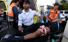 A wounded Israeli man is taken to an ambulance after his wounded leg was bandaged at the scene of an attack at a synagogue in a religious area of Jerusalem, 18 November 2014. Picture: EPA.