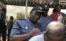A SAPS official signs a document during a protest in Polokwane where residents called for justice after the murder of Thoriso Themane. Picture: Thando Kubheka/EWN.