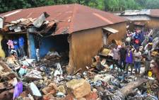 People stand near a damaged house after a rubbish dump collapsed the day before following heavy rain on the outskirts of Conakry. Picture: AFP.