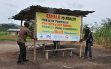 World Health Organisation volunteers putting up a banner warining people about the realness of the Ebola outbreak in West Africa. Picture: Official WHO Facebook page.