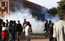 Sudanese protesters scatter from tear gas fired by security forces during a rally to mark three years since the start of mass demonstrations that led to the ouster of strongman Omar al-Bashir, near the presidential palace in the capital Khartoum on 19 December 2021. Picture: AFP