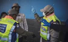 South African Metro policemen try to enforce distancing outside a supermarket in Hillbrow, Johannesburg, on 27 March 2020 where several dozens of customers are queuing for food without respecting the minimum safety distance. Picture: AFP
