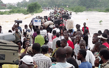 FILE: Travellers heading to Cape Coast from Accra carry their belongings on their heads on June 21, 2010 after the road was cut by floods. Picture: AFP.