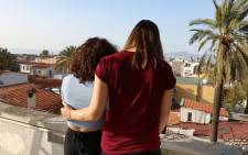 A female couple from Cyprus' LGBTQ+ community stand together on a rooftop in the old city of the capital Nicosia on April 2, 2022. Cypriot lawmakers and activists are pushing to criminalise "gay conversion therapy" which has left members of the island's LGBTQ+ community traumatised through "medieval" practices such as exorcisms. Picture: Aline Manoukian / AFP