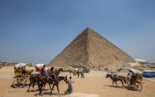 Egyptians ride their carts past the Great Pyramid of Cheops, aka Pyramid of Khufu, on 31 August 2016 on the Giza Plateau, on the southern outskirts of the capital Cairo. Picture: AFP.