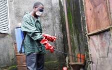 A local volunteer with NGO Action against Hunger sprays disinfectant at a home where three people were infected with cholera. Dabondy neighbourhood of the Guinean capital Conakry. Picture: Irin news.