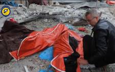 An image grab from a video released by the Syrian Civil Defence in Aleppo on 30 November 2016, reportedly shows a man covering a body lying on a street in the rebel-held district of Jubb al-Qubbeh in eastern Aleppo following government artillery fire. Picture: AFP.