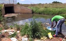 A young man washing his clothes in a sewage filled stream in Protea South in Soweto. Picture: Reinart Toerien/EWN.