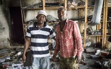 Razak and his brother Daniel Agbenoza stand in their burnt out workshop, after looters broke in, stealing valuables, and setting fire to the building. Picture: Thomas Holder/EWN