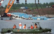 Rescue workers look at the sunken passenger ship as it is lifted by cranes in the Yangtze river in Jianli in China's Hubei province on 5 June, 2015. Picture: AFP.