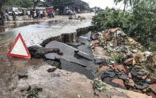 Residents stand next to a road partially destroyed by floods after heavy downpours in Pemba, on 28 April 2019, after the destruction caused by Cyclone Kenneth. Picture: AFP