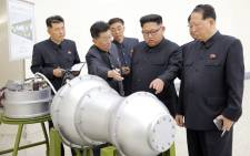This undated picture released by North Korea's official Korean Central News Agency (KCNA) on 3 September 2017 shows North Korean leader Kim Jong-Un (C) looking at a metal casing with two bulges at an undisclosed location. Picture: AFP.