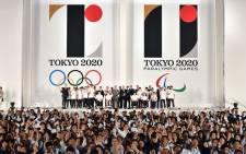 FILE: People wave Olympic flags as the logo marks of the Tokyo 2020 Olympic and Paralympic Games are unveiled at the Tokyo city hall on 24 July 2015. Picture: AFP.
