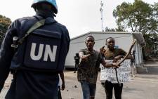 A UN soldier is seen as demonstrators carry a poster against the peacekeeping mission in the Democratic Republic of Congo (MONUSCO) at the UN facilities in Goma on July 25, 2022. Protesters stormed a United Nations base in the eastern Congolese city of Goma today, an AFP journalist said, demanding the departure of peacekeepers from the region. Picture: Michel Lunanga / AFP