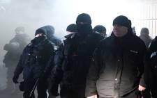 Police officers stand in front of the Russian Embassy in Kiev late on 25 November, 2018, while smoke from a flare thrown by protesters is seen during a rally following an incident in the Black Sea off Moscow-annexed Crimea, in which three Ukrainian naval vessels were seized by a Russian border guard vessel, as the three ships were on their way through the Kerch Strait heading for the port of Mariupol. Picture: AFP