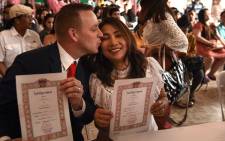 A Thai woman and a British man hold up their marriage certificates on Valentine's Day at the central post office in the Bang Rak, or 'Love Village', district in Bangkok on 14 February 2018. Picture: AFP