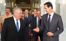 FILE: This handout picture released by the Syrian Presidency Facebook page on 25 July 2018, shows President Bashar al-Assad (R) welcoming Russian President's Special Envoy to Syria Alexander Lavrentiev (L) in Damascus. Picture: AFP

