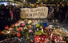 People hold a banner reading in French and Flamish âI AM BRUSSELSâ as they gather around floral tributes, candles, belgian flags and notes in front of the Bourse of Brussels on 22 March, 2016 in tribute to the victims of Brussels following triple bomb attacks in the Belgian capital that killed about 35 people and left more than 200 people wounded. Picture: AFP.
