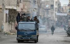 FILE: Rebels stand on the back of a pick-up truck driving through the eastern Syrian town of Deir Ezzor on 10 March, 2014. Picture: AFP.