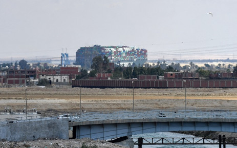 This picture taken on March 28, 2021 shows a distant view of the Panama-flagged MV 'Ever Given' (operated by Taiwan-based Evergreen Marine) container ship, which has been wedged diagonally across the span of the canal about six kilometres north of the Suez Canal's entrance by the Red Sea port city of Suez since March 23, blocking the waterway in both directions. Picture: Ahmed HASAN / AFP.