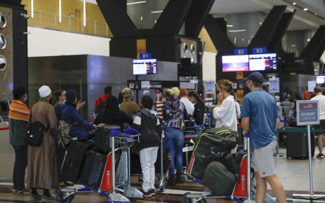 Travellers queue at a check-in counter at OR Tambo International Airport in Johannesburg on 27 November 2021.