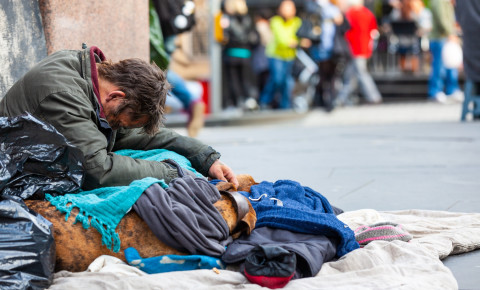 homeless-man-sitting-on-city-street-corner-people-passing-byjpg