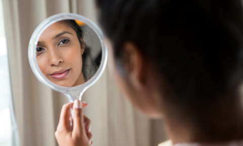 Woman looking at herself in hand mirror 123rf