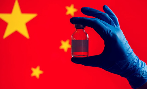 gloved-hand-holding-vaccine-in-front-of-chinese-flagjpg