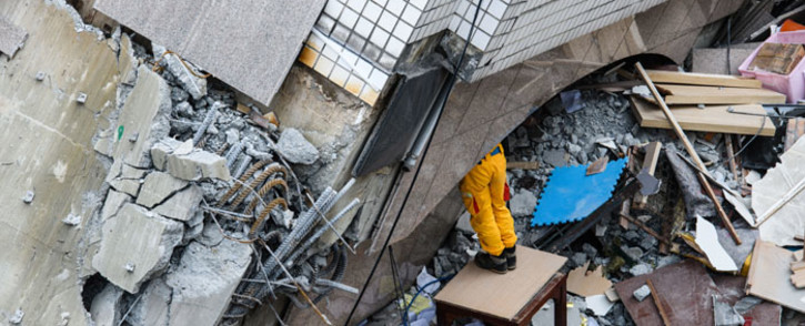 A rescue worker clears debris to make way for the recovery of the dead bodies of a Hong Kong Canadian couple from the Yun Tsui building, in the Taiwanese city of Hualien on 9 February 2018, following a 6.4-magnitude quake. Picture: AFP