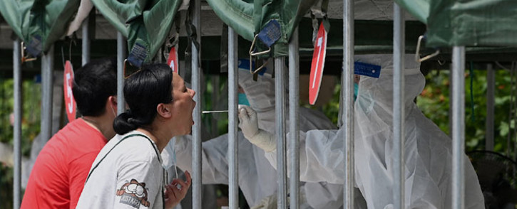 FILE: A health worker takes a swab sample from a woman to be tested for the COVID-19 coronavirus at a nucleic acid sample collection station at a park in Beijing on 5 August 2021. Picture: Noel Celis/AFP