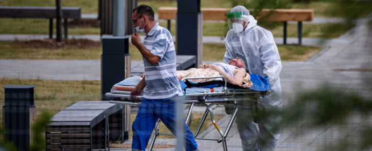 Medics escort a woman into a hospital where patients infected with the COVID-19 novel coronavirus are being treated in the settlement of Kommunarka outside Moscow, Russia, on 30 June 2021. Picture: Dimitar DILKOFF/AFP