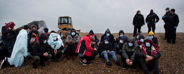 Migrants sit on the beach after being helped ashore from a RNLI (Royal National Lifeboat Institution) lifeboat at a beach in Dungeness, on the south-east coast of England, on 24 November 2021, after being rescued while crossing the English Channel. Picture: Ben STANSALL/AFP 