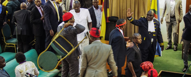 Ugandan Opposition MP Allan Ssewanyana (C) holds a chair as he stands on a table after unseen Speaker Rebecca Kadaga asked him and another 24 lawmakers to leave during the plenary session at The Ugandan Parliament in Kampala on 27 September 2017. Picture: AFP