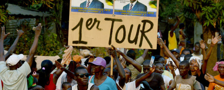 Supporters of Central African presidential candidate Faustin Archange Touadera hold a placard with Touedara's campaign poster and reading "1st tour" during a presidential campaign rally in Bangui on 28 December 2015, on the last day of campaigning ahead of Central African Republic presidential and legislative elections. Picture: AFP.