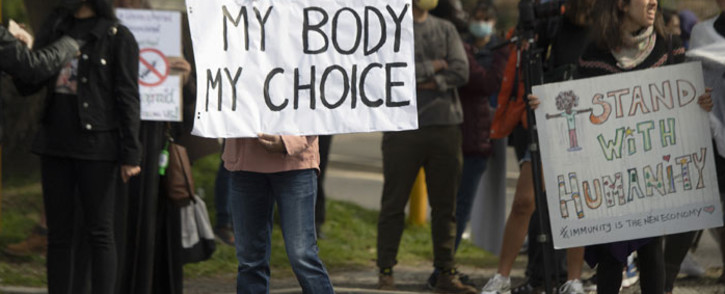 FILE: Demonstrators hold up banners and placards during a protest against COVID-19 vaccinations in front of Groote Schuur Hospital in Cape Town on 21 August 2021.Picture: Rodger Bosch/AFP