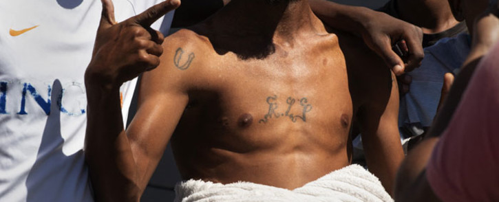 FILE: A group of young men, one with a tattoo 'RIP' (Rest in Peace), pose for photos during a police crime-prevention operation in Mitchells Plain in Cape Town on 5 March 2021 during a joint operation between SAPS and provincial Law Enforcement officers. Picture: Rodger Bosch/AFP