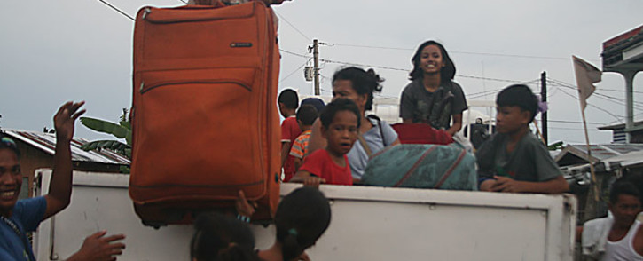 Residents carry their belongings onto a government vehicle as they evacuate from their tent houses to a safer place in Tacloban City, central Philippines on 4 December 4, 2014, ahead of the landfall of super Typhoon Hagupit. Picture: AFP.