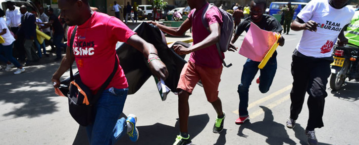 Civil rights activists run to escape teargas as a canister goes-off on the ground during a demonstration on 5 February, 2018 in the streets of Nairobi. Picture: AFP