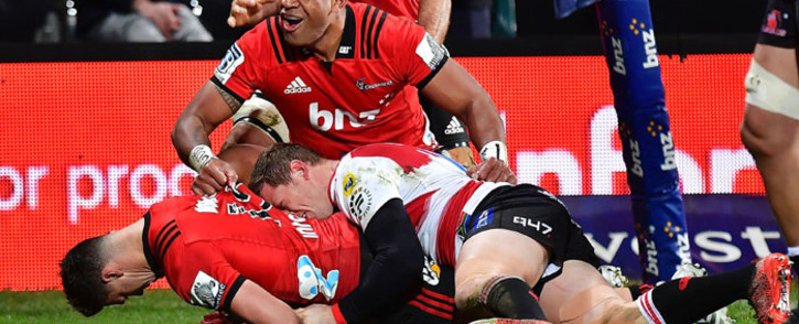 The Crusaders' David Havili (left) scores a try after being tackled by the Lions' Ruan Combrinck (centre right) as the Crusaders' Seta Tamanivalu (top) celebrates during the Super Rugby final at the AMI Stadium in Christchurch on 4 August, 2018. Picture: AFP