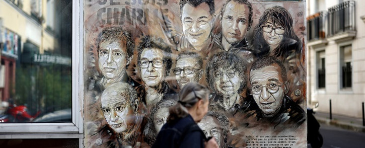 A woman walks past a painting by French street artist and painter Christian Guemy, known as C215, in tribute to members of 'Charlie Hebdo' newspaper who were killed by jihadist gunmen in January 2015, in Paris, on 31 August 2020. Picture: AFP