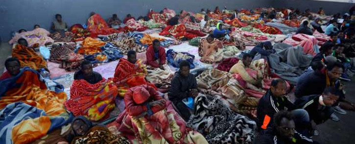 A picture taken on 11 December 2017 shows African migrants sitting in a shelter at the Tariq Al-Matar migrant detention centre on the outskirts of the Libyan capital Tripoli. Picture: AFP