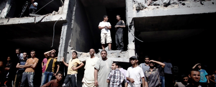 FILE: Palestinians gather on the rubble and shell of a building destroyed following an Israeli military strike, as they watch rescuers working in Rafah in the south of the Gaza Strip, on 21 August 2014. Picture: AFP.