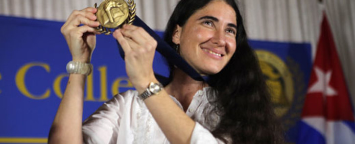 Cuban blogger and independent journalist Yoani Sanchez holds up a Presidential Medal of Miami Dade College given to her during an event at the Miami Dade College’s Freedom Tower on 1 April 2013 in Miami, Florida. Picture: AFP