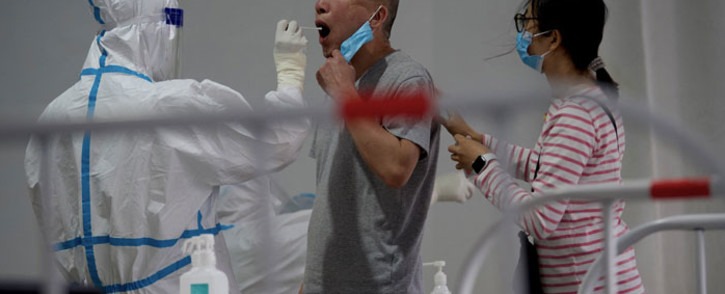 A health worker takes a swab sample on a man to be tested for COVID-19 coronavirus at a swab collection site along a street in Beijing on 25 April 2022. Picture: Noel Celis/AFP