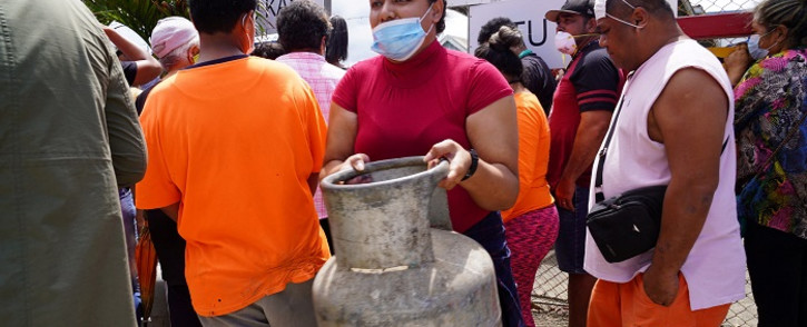 A woman (C) carries a refilled gas container in the centre of the capital Nuku'alofa ahead of the country's first lockdown on 2 February 2022, after COVID-19 was detected in the previously virus-free Pacific kingdom as it struggles to recover from the deadly 15 January volcanic eruption and tsunami. Picture: Mary Lyn Fonua/ Matangi Tonga/AFP