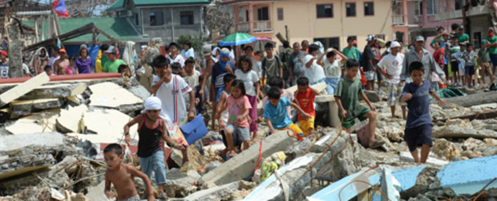 Residents walk through debris as they rush to a rescue helicopter delivering relief foods in Hernani town, Eastern Samar province, central Philippines on 11 November, 2013, four days after Typhoon Haiyan hit the country. Picture:AFP